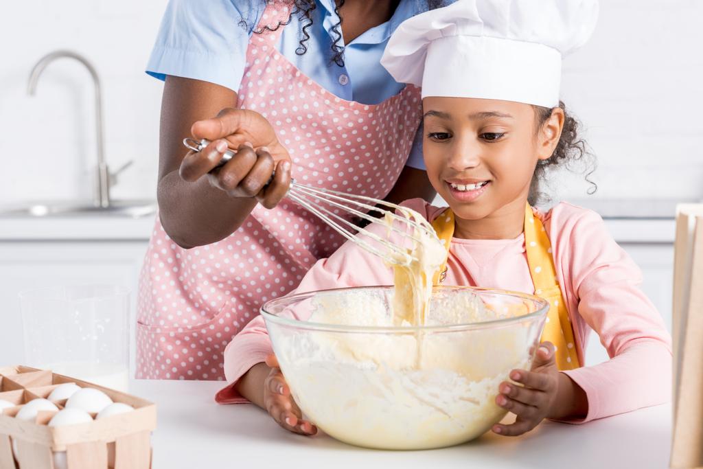 Αφρικανική αμερικανική μητέρα και κόρη στην καπέλο σεφ ζύμες στην κουζίνα - Φωτογραφία, εικόνα