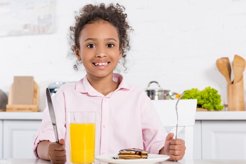 cheerful african american kid having pancakes and orange juice for breakfast - Photo, Image