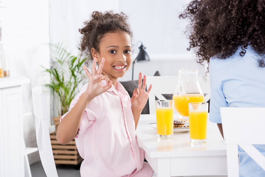 afro-américaine mère et fille montrant ok signes pendant le petit déjeuner dans la salle à manger
 - Photo, image