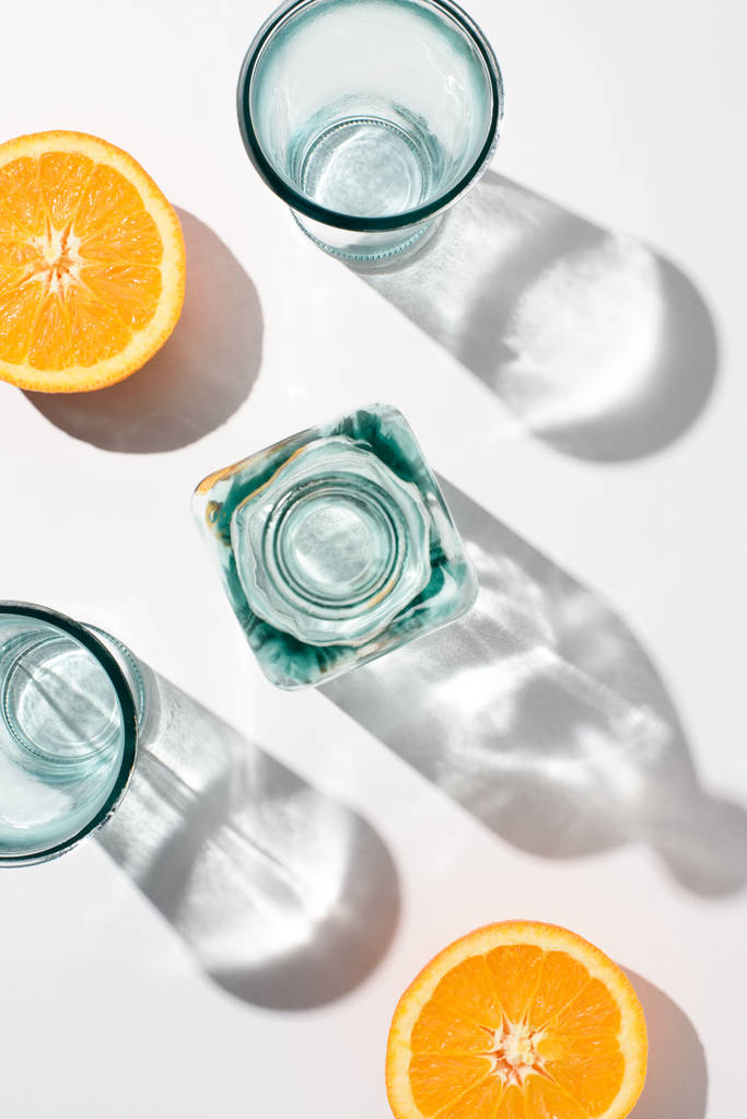 top view of pieces of orange, bottle and empty glasses on white surface - Photo, Image