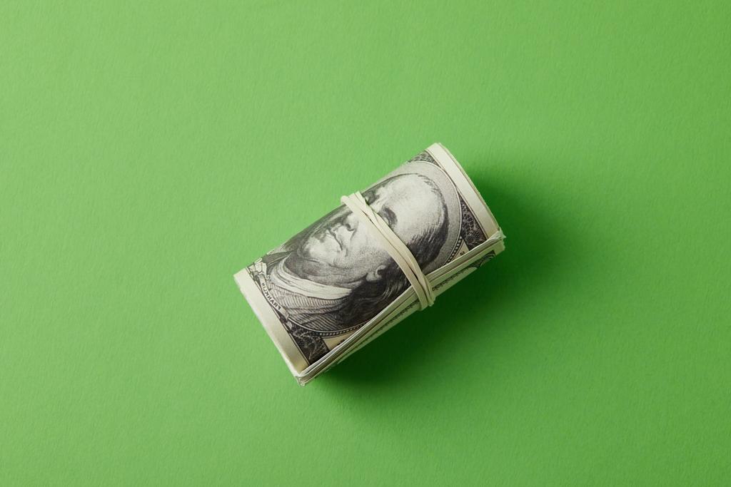 pohled shora roll dolarů převázaná gumičkou na zelené - Fotografie, Obrázek