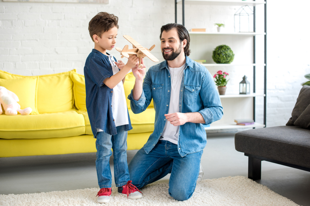 glücklicher Vater und süßer kleiner Sohn spielen zu Hause mit Holzspielzeug  - Foto, Bild