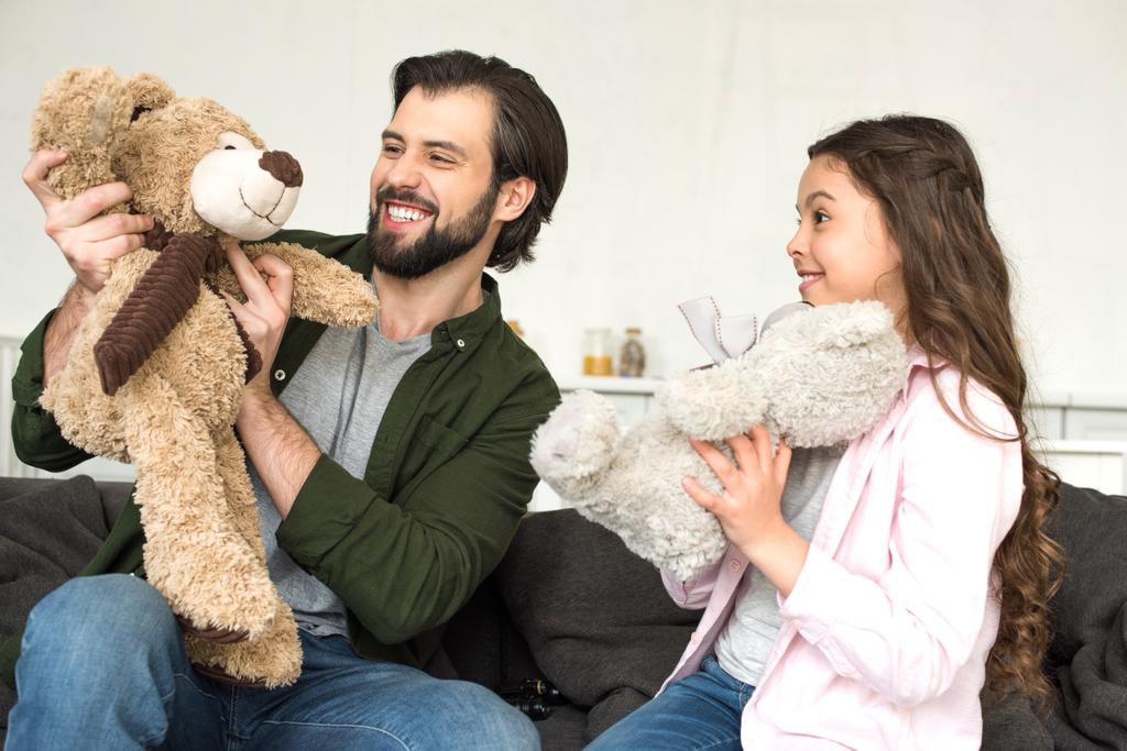 pai feliz e filha brincando com ursos de pelúcia em casa
  - Foto, Imagem