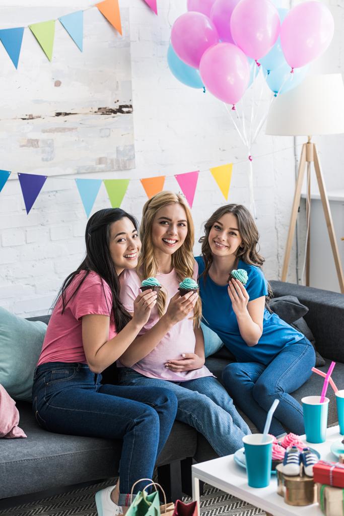 πολυπολιτισμική τους φίλους χαμογελώντας και έγκυος γυναίκα με cupcakes στο κόμμα-το μωρό - Φωτογραφία, εικόνα