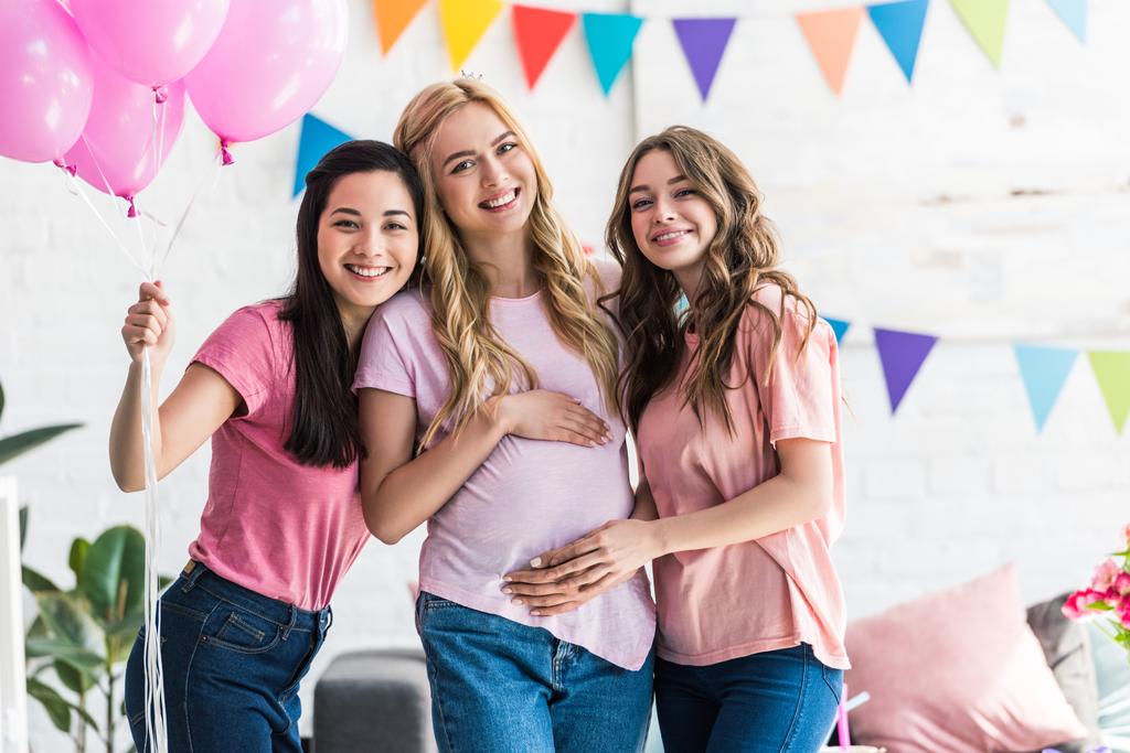 donne multiculturali sorridenti che toccano la pancia di un'amica incinta alla festa del bambino
 - Foto, immagini