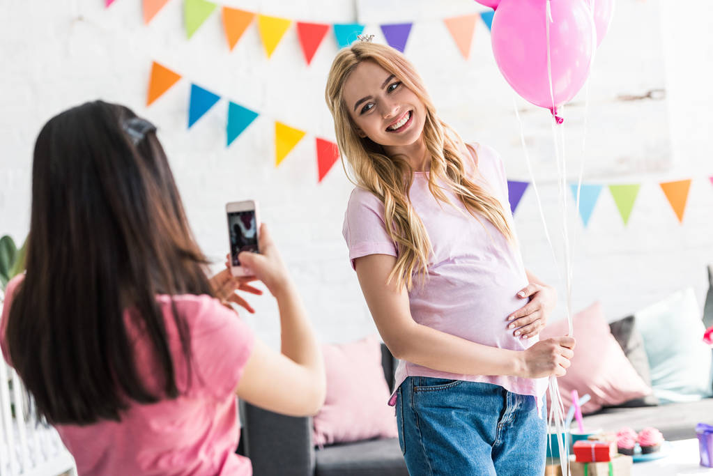 menina tirando foto de amigo grávida na festa do chuveiro do bebê
 - Foto, Imagem