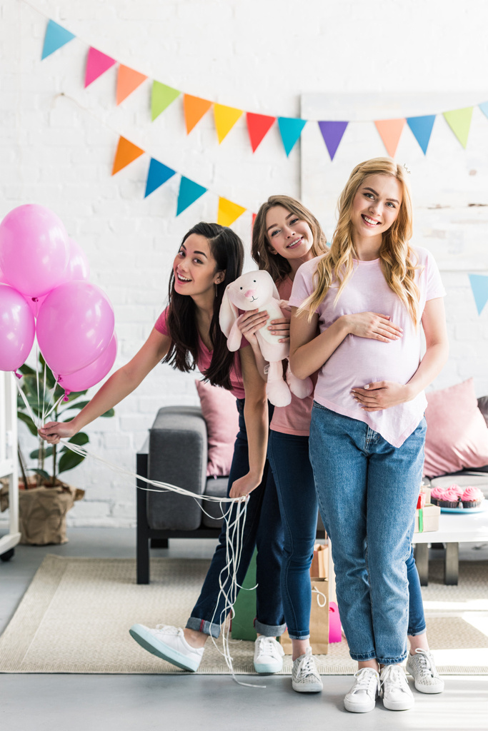 szczęśliwy przyjaciele wielokulturowym i kobieta w ciąży z zabawka królik baby shower party - Zdjęcie, obraz