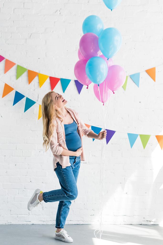 vista laterale di felice bella donna incinta in possesso di fascio di palloncini a baby-party
 - Foto, immagini