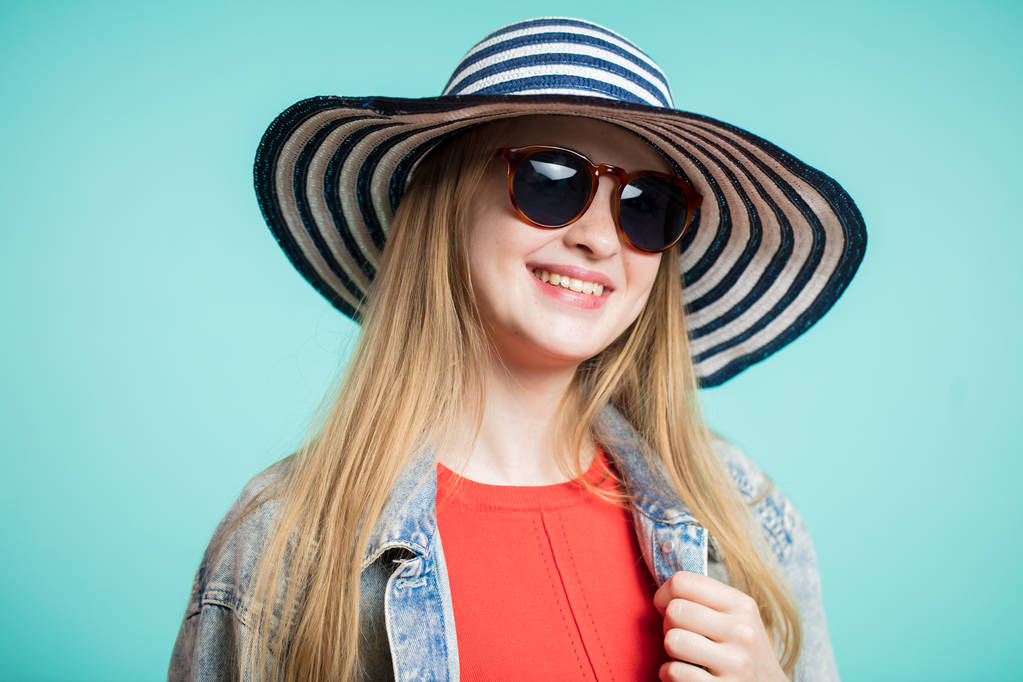 Güneş gözlüklü genç kadın görüntüsünü kapatın ve şapka bir gülümseme ile kameraya benziyor. - Fotoğraf, Görsel