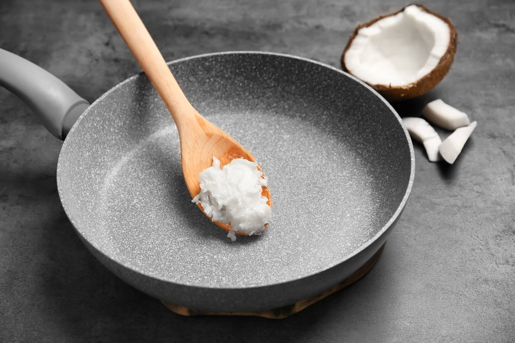 Сковородка с кокосовым маслом и орехами на сером фоне
 - Фото, изображение