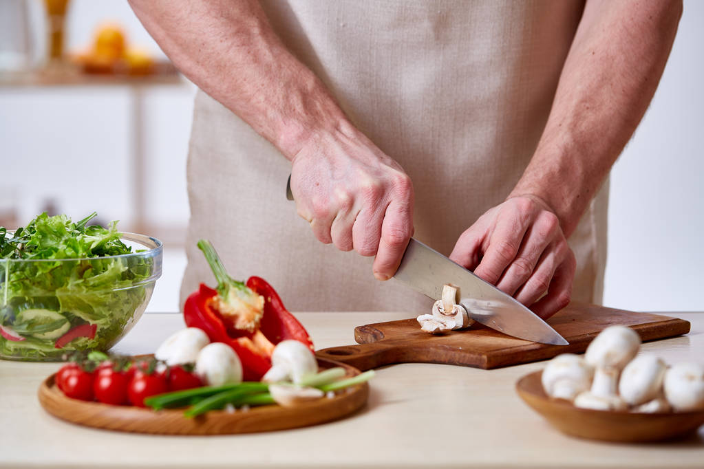 Homme cuisinant à la cuisine faisant salade de légumes sains, gros plan, mise au point sélective
. - Photo, image