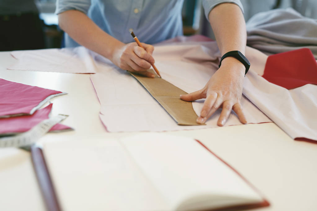 Alfaiate feminino fazendo padrões de costura na mesa
 - Foto, Imagem