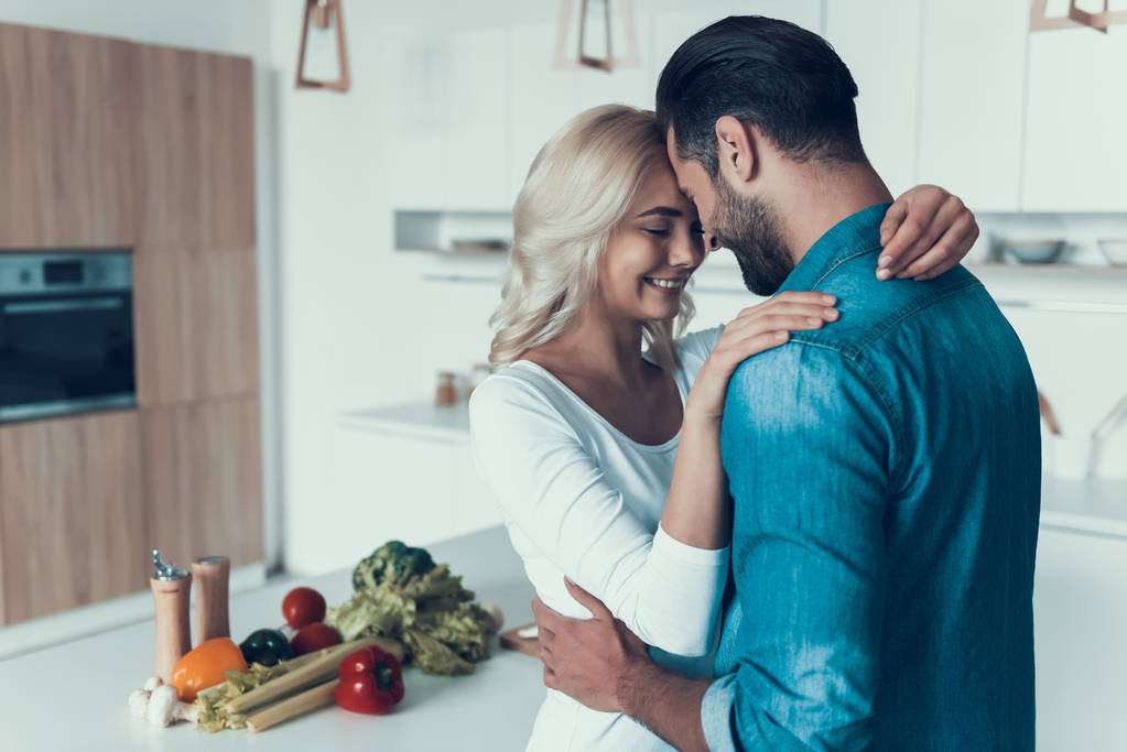 Ευτυχισμένο ζευγάρι αγκαλιάζει στην κουζίνα. Ρομαντική σχέση. - Φωτογραφία, εικόνα