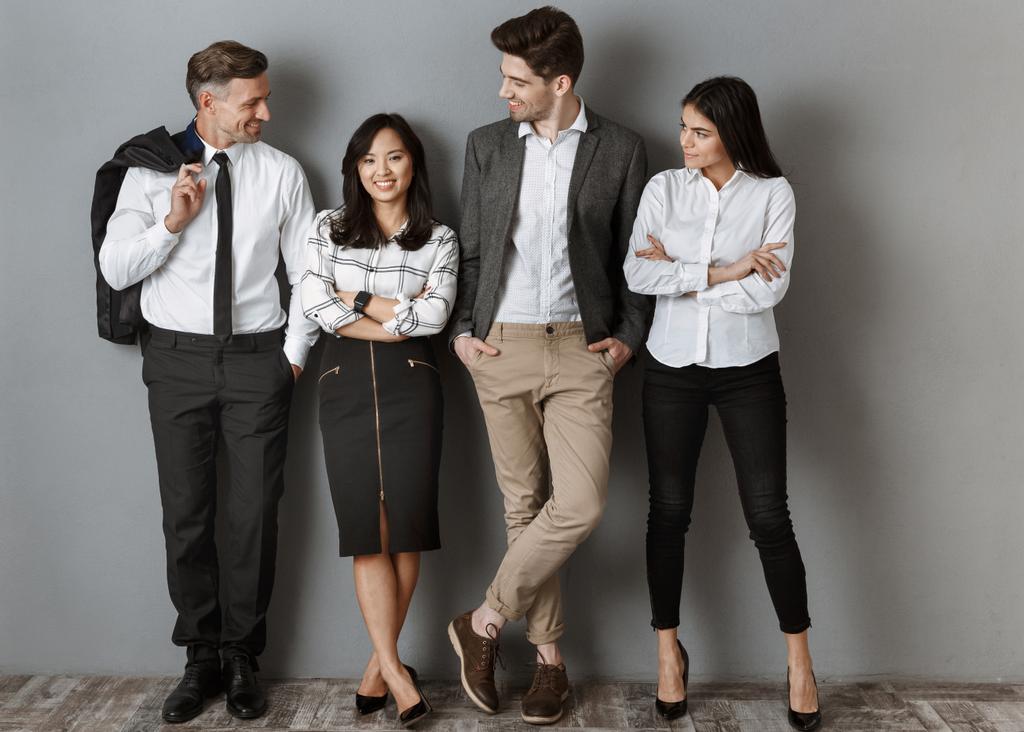gente de negocios multicultural sonriente en ropa formal de pie en la pared gris
 - Foto, Imagen