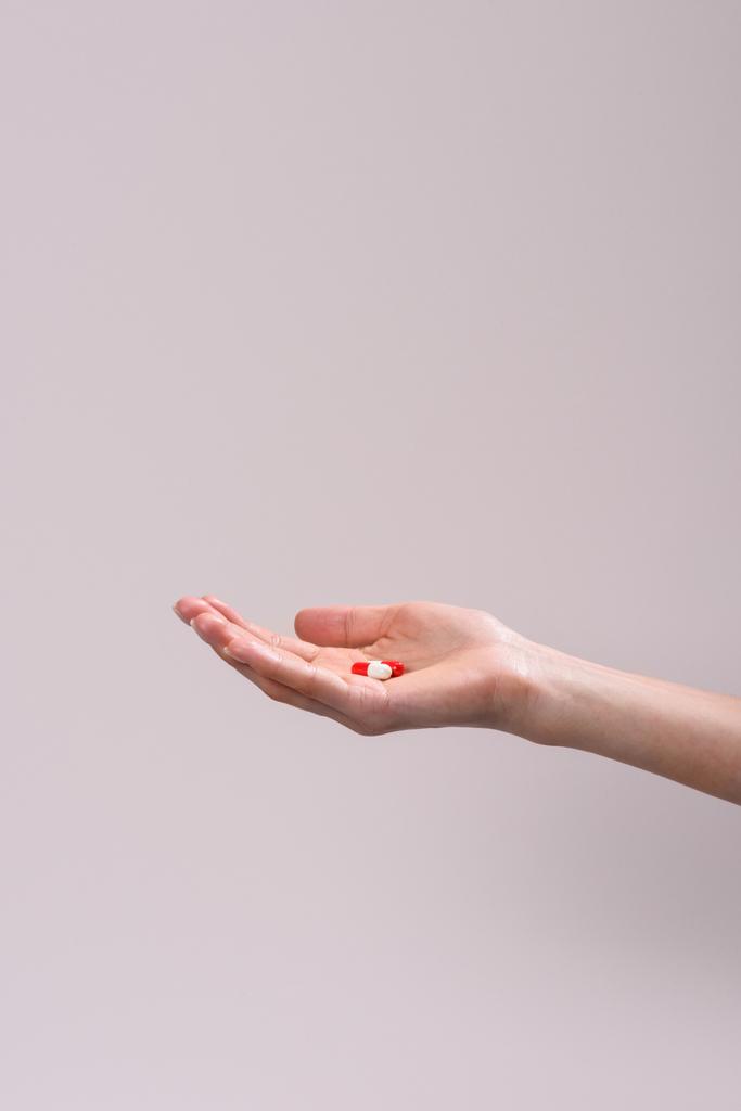 Abgeschnittene Aufnahme einer Frau mit einem Stapel Pillen in der Hand isoliert auf grau - Foto, Bild