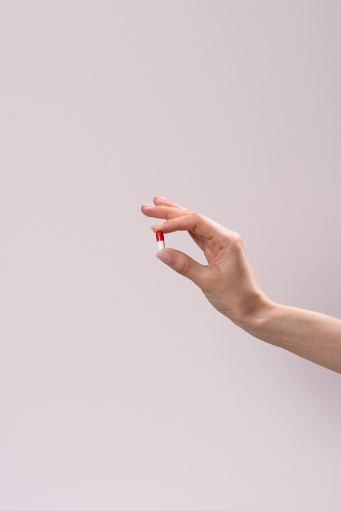 обрезанный снимок женщины, держащей капсулу с наркотиками, изолированную на серой
 - Фото, изображение