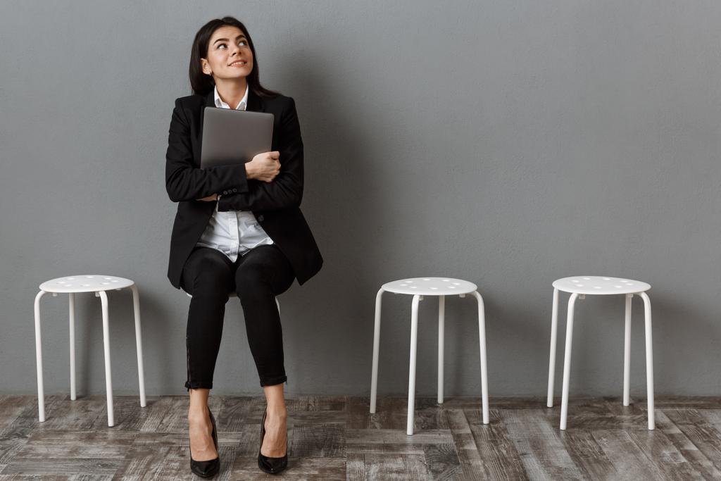 就職の面接を待っているラップトップでスーツの物思いにふける女性実業家 - 写真・画像
