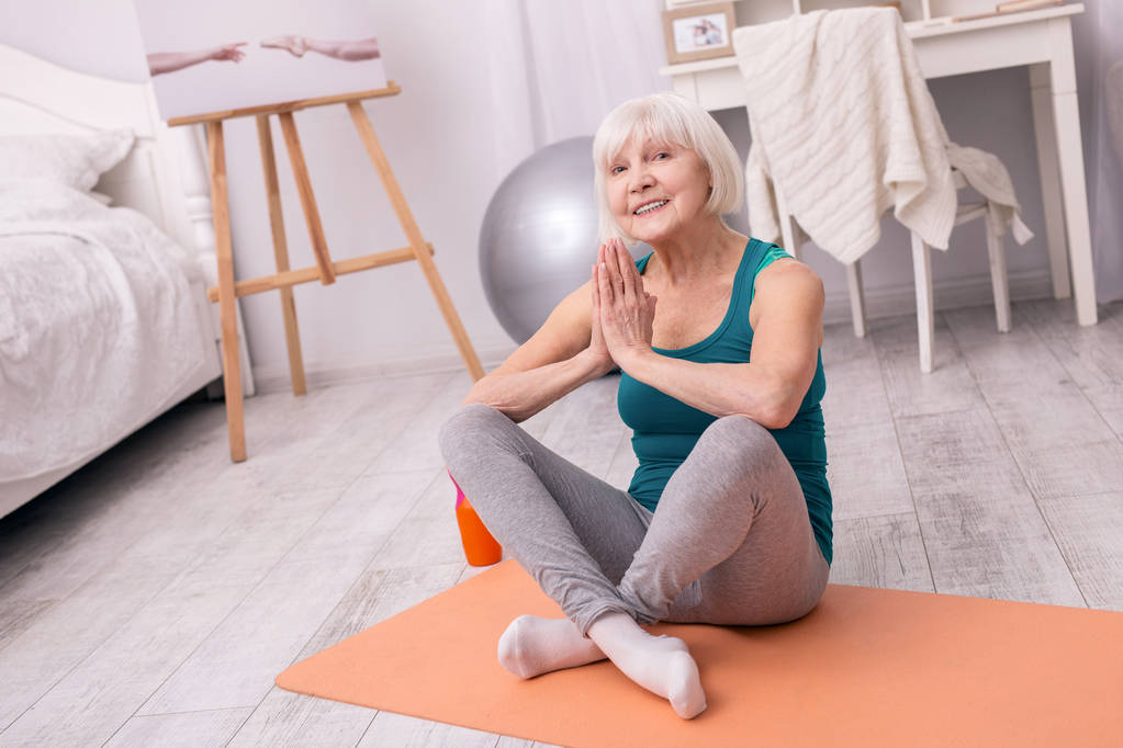 Pozitivní starší žena pózuje při cvičení jógy - Fotografie, Obrázek