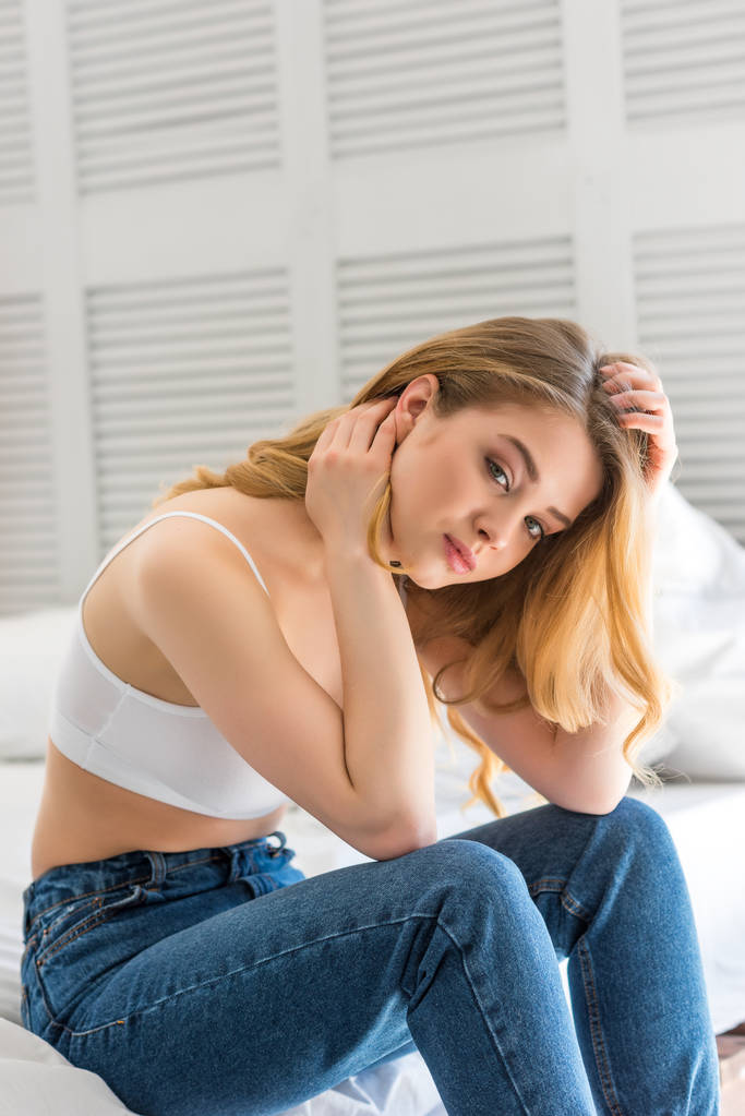 hermosa chica en jeans y sujetador blanco sentado en la cama
  - Foto, Imagen