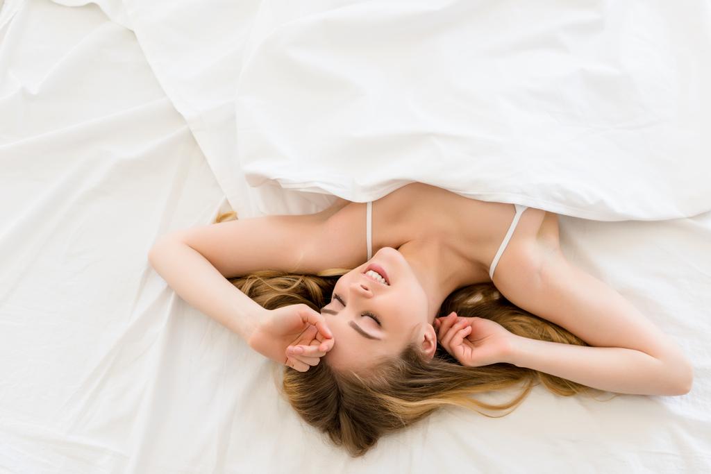 top näkymä houkutteleva hymyilevä tyttö rentouttava sängyllä aamulla
 - Valokuva, kuva