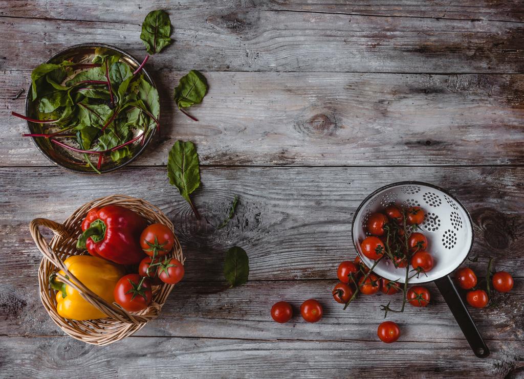 vista superior de la cesta de mimbre, plato, colador, tomates cherry, pimientos y hojas de mangold en la mesa de madera
  - Foto, Imagen