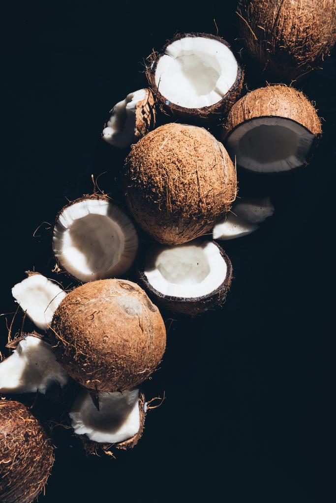 Widok z góry z całego i pęknięty ekologicznych kokosów na czarnym tle - Zdjęcie, obraz
