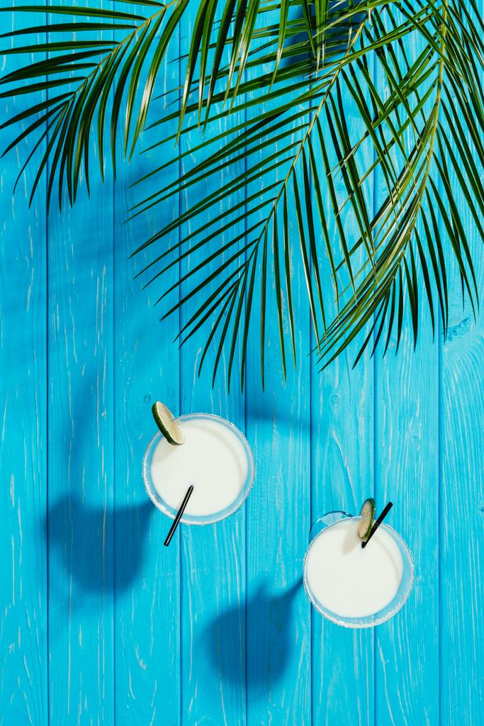vista dall'alto di cocktail di cocco in bicchieri e foglie di palma verde sul tavolo in legno turchese
 - Foto, immagini