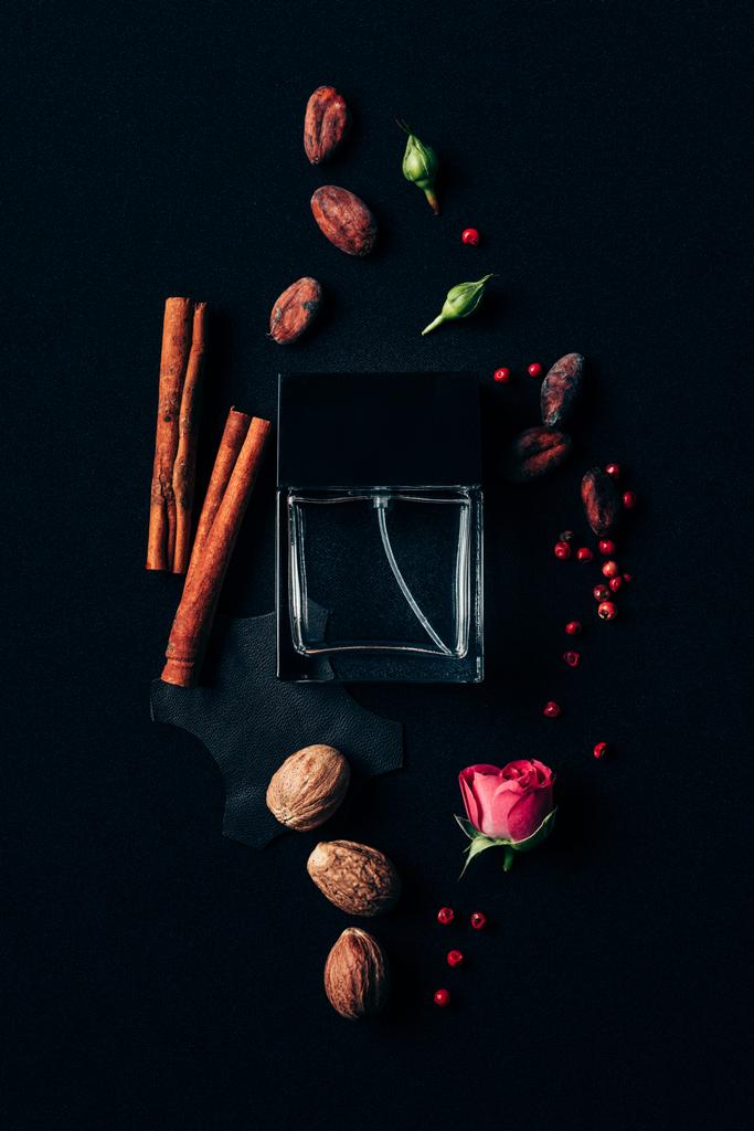 top view of bottle of perfume surrounded with aromatic spices on black - Photo, Image