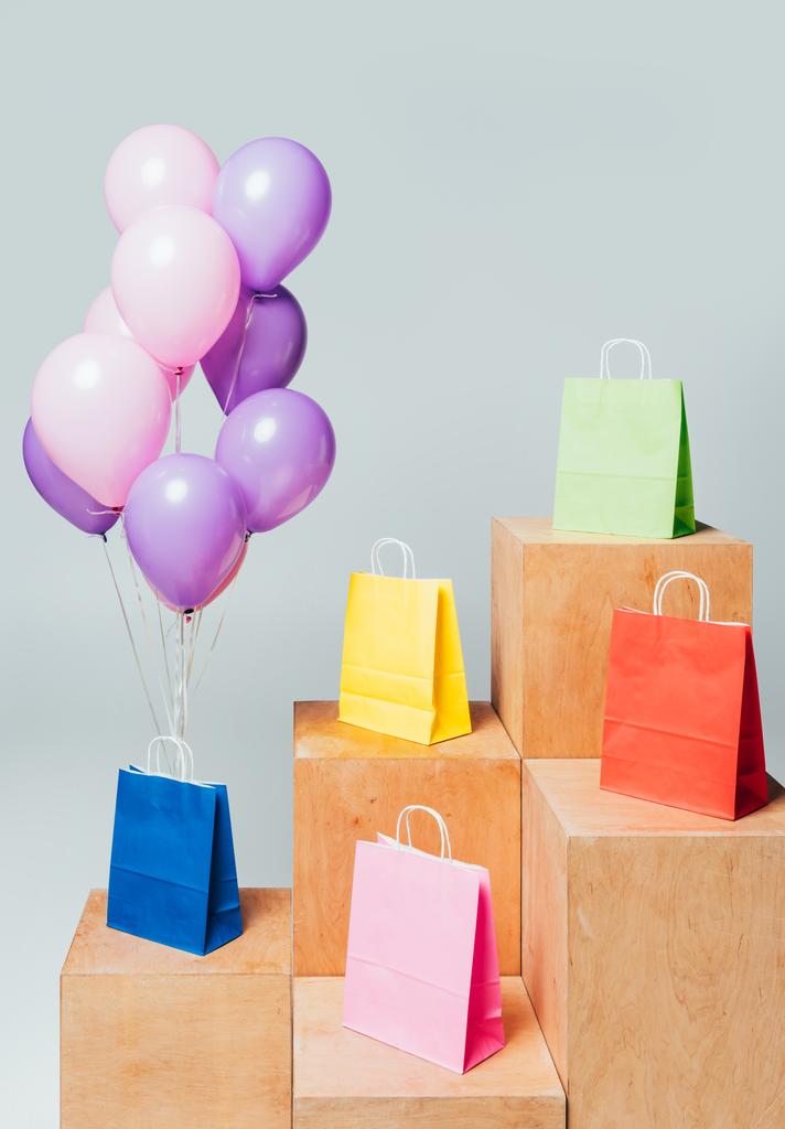 bundel van roze en paarse ballonnen in de buurt van papieren zakken op stands geïsoleerd op wit, zomer verkoop concept - Foto, afbeelding