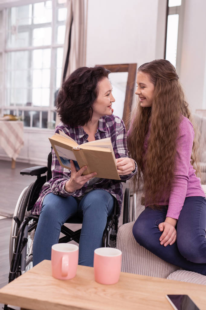 Inspirowane niepełnosprawnych kobieta i dziewczynka studiując książki - Zdjęcie, obraz