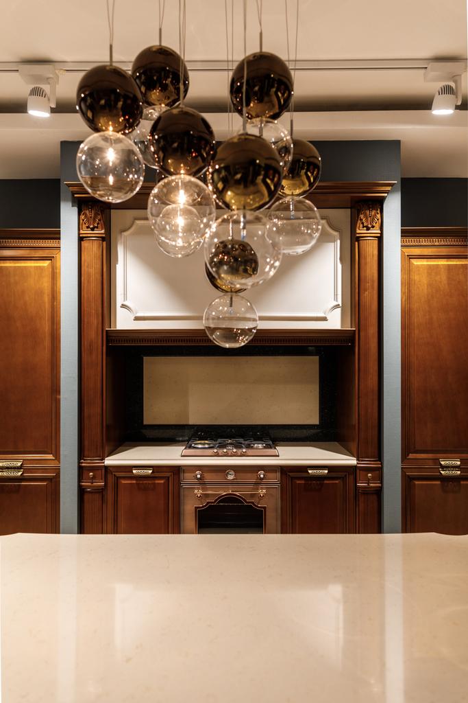 Стильная кухня с элегантным блестящим столом и люстрой
 - Фото, изображение