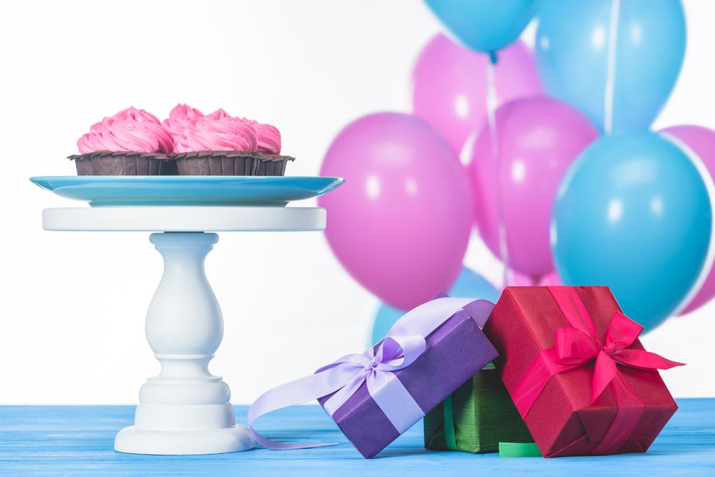 cajas de regalo y cupcakes en pie de pastel aislado en blanco
 - Foto, imagen