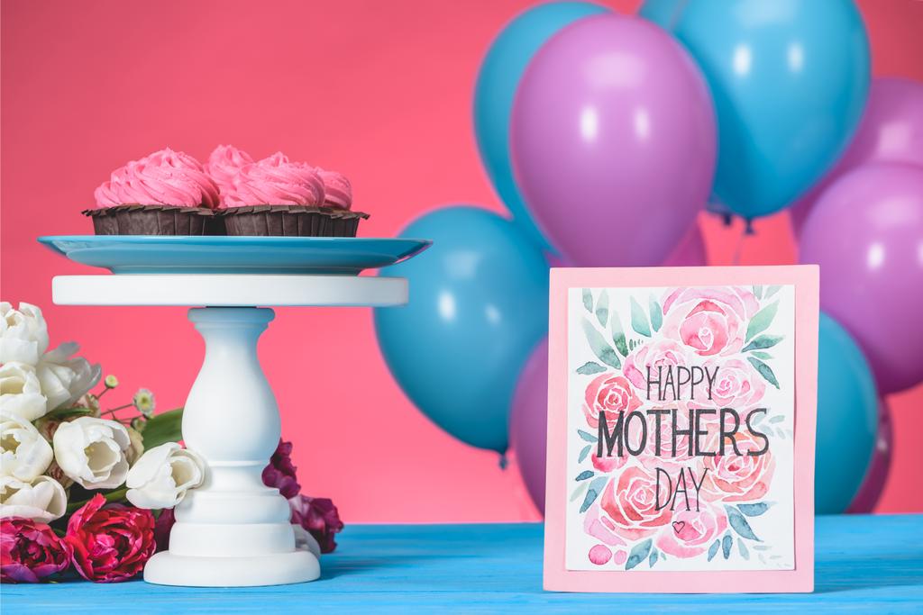 ansichtkaart met tekst Happy Mothers Day en roze cupcakes op cake stand - Foto, afbeelding