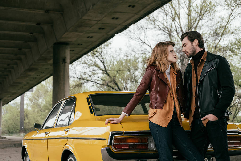 belo jovem casal apaixonado olhando um para o outro, enquanto de pé perto do carro clássico amarelo
 - Foto, Imagem