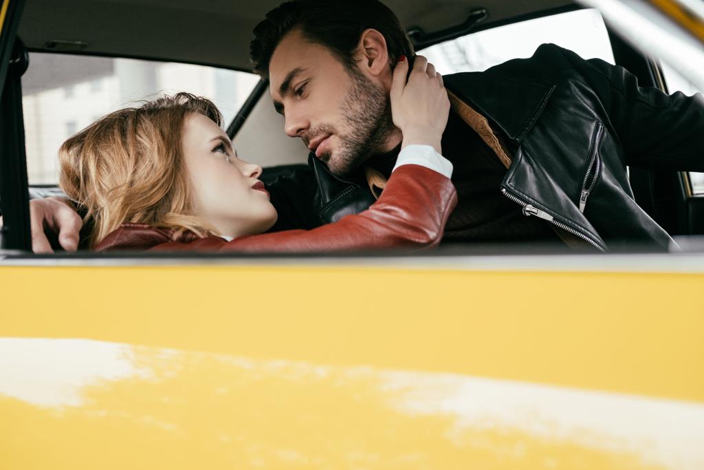 beautiful stylish young couple hugging and looking at each other in car  - Photo, Image