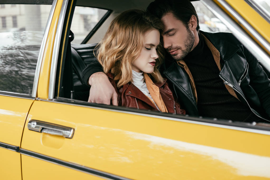 bella tenera giovane coppia con gli occhi chiusi che abbraccia in auto gialla
 - Foto, immagini