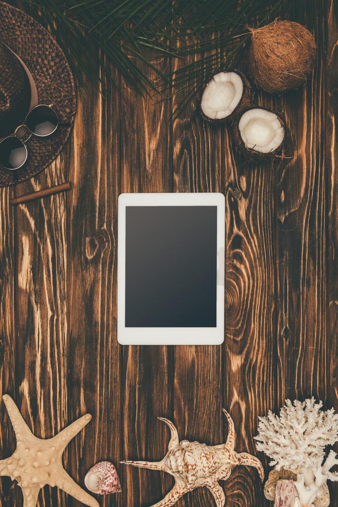 vista dall'alto del tablet digitale su una superficie di legno circondata da vari attributi di viaggio tropicale
 - Foto, immagini