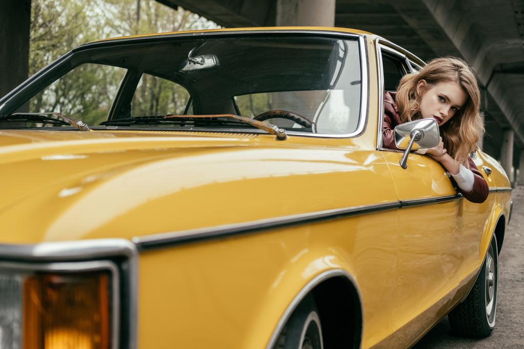 attraente giovane donna guardando la fotocamera mentre seduto in giallo auto d'epoca
 - Foto, immagini