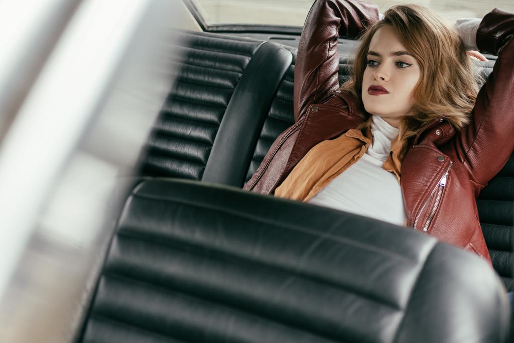 foyer sélectif de belle fille sensuelle en veste en cuir assis dans la voiture et regardant loin
 - Photo, image
