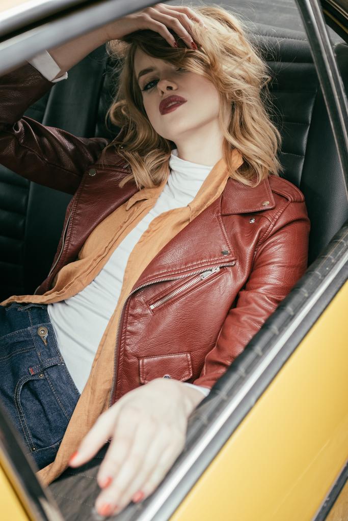 menina sedutora em jaqueta de couro sentado no carro clássico e olhando para a câmera
 - Foto, Imagem