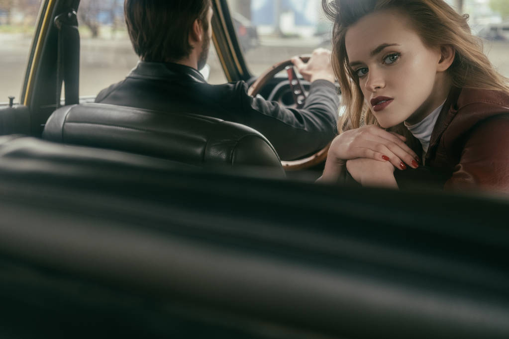 selectieve aandacht van aantrekkelijk meisje camera kijken tijdens de vergadering in auto met knappe vriendje - Foto, afbeelding