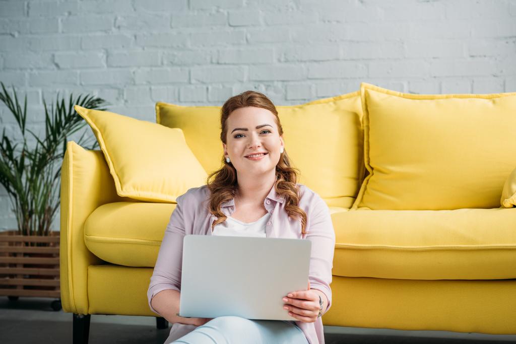 smiling beautiful woman holding laptop and looking at camera at home - Photo, Image