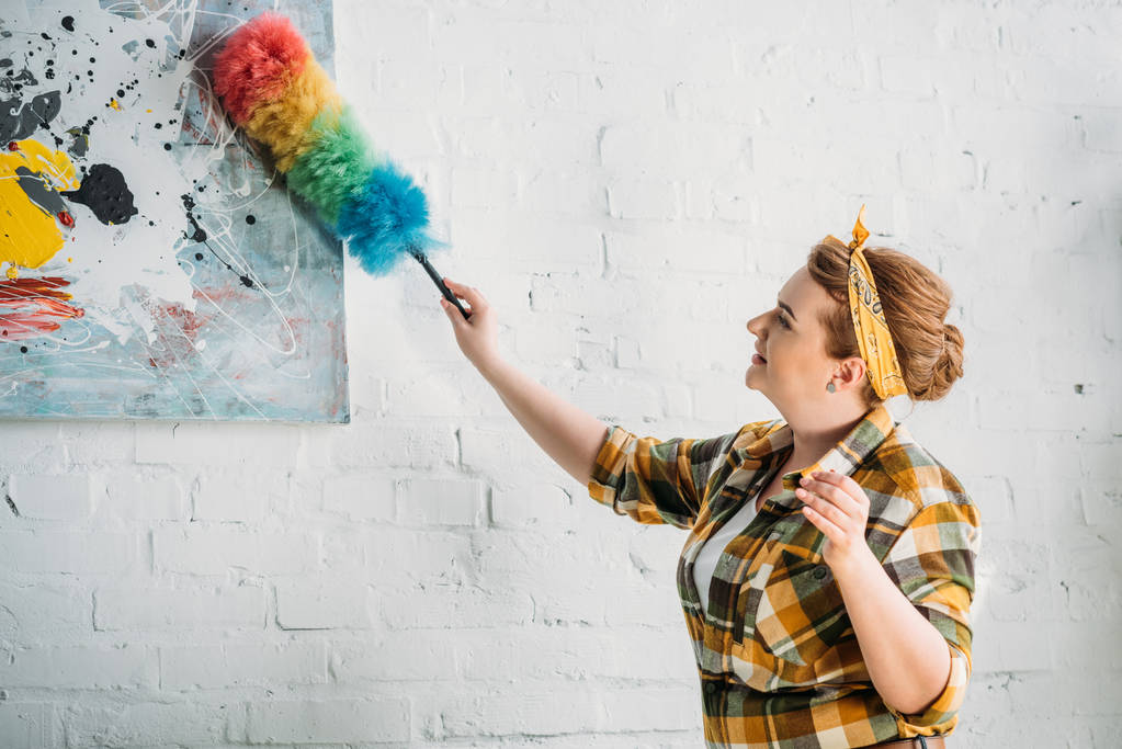 hermosa mujer desempolvando pintura en la pared en casa
 - Foto, imagen