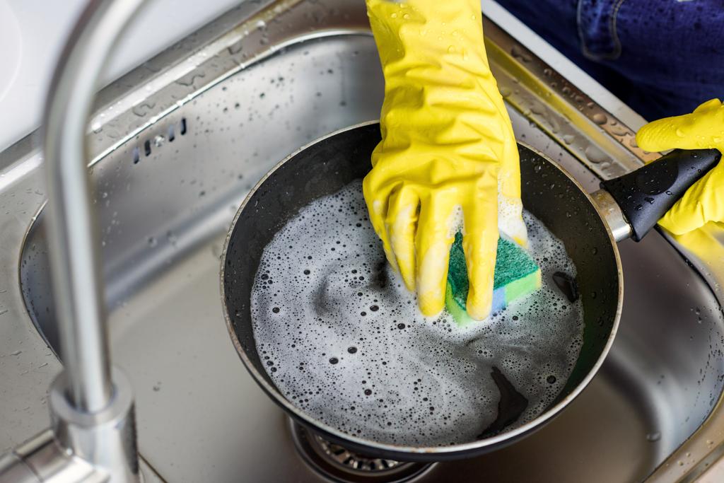 abgeschnittenes Bild einer Frau, die in der Küche Pfanne wäscht - Foto, Bild