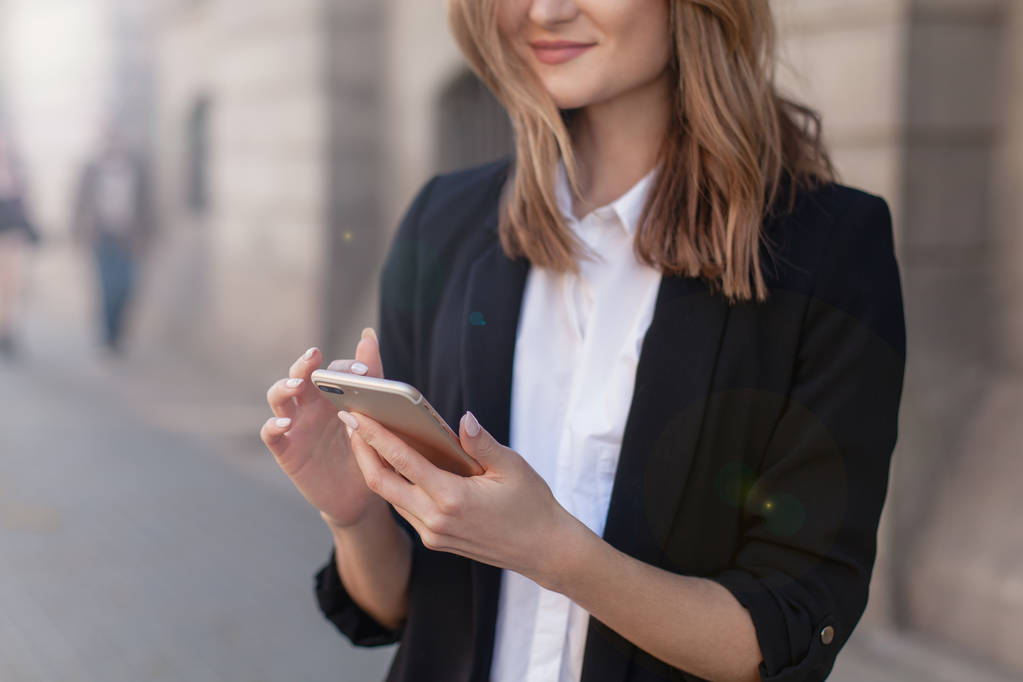 Schnappschuss eines jungen Mädchens mit modernem Smartphone-Gerät, weibliche Hände, die ihr Mobiltelefon auf der Straße halten, lächelnde erfolgreiche Unternehmerin, die eine drahtlose Handy-Verbindung für die Arbeit im Freien nutzt - Foto, Bild