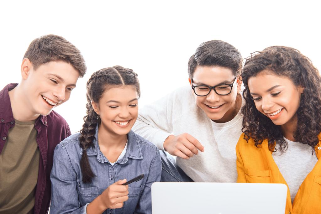 портрет улыбающихся многонациональных друзей-подростков, использующих ноутбук вместе изолированные на белом
 - Фото, изображение