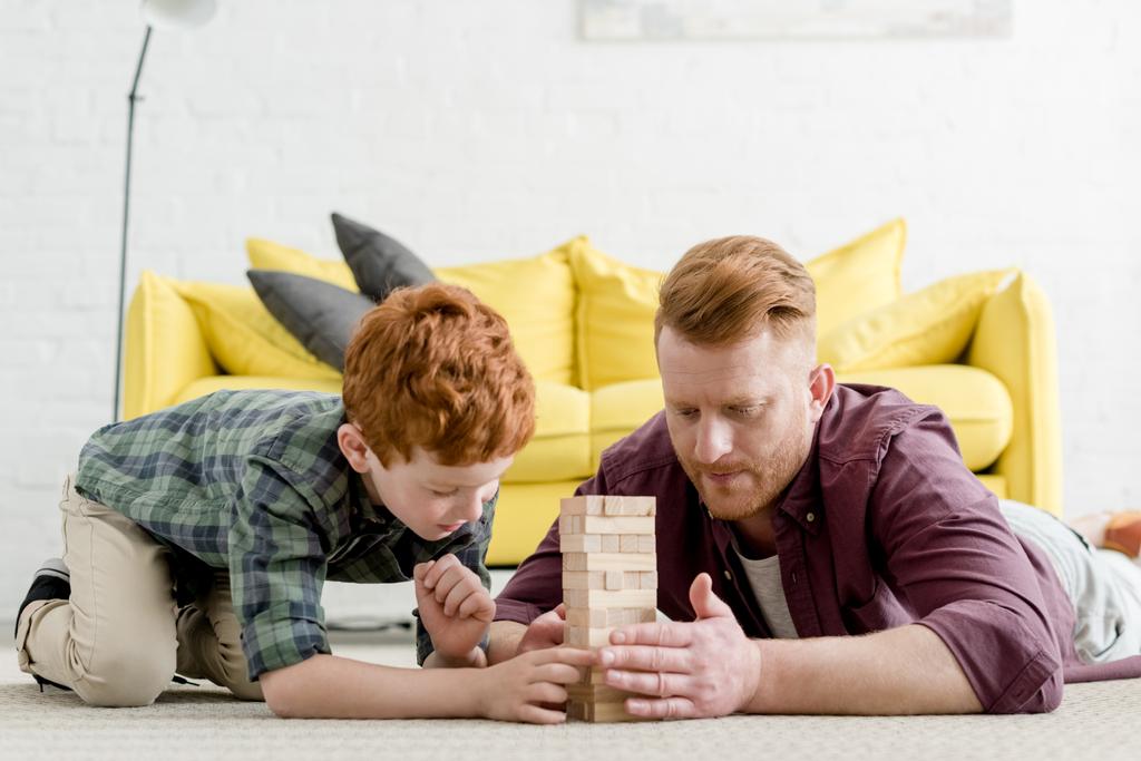 εστιασμένη πατέρας και γιος παίζει με ξύλινα μπλοκ στο σπίτι - Φωτογραφία, εικόνα