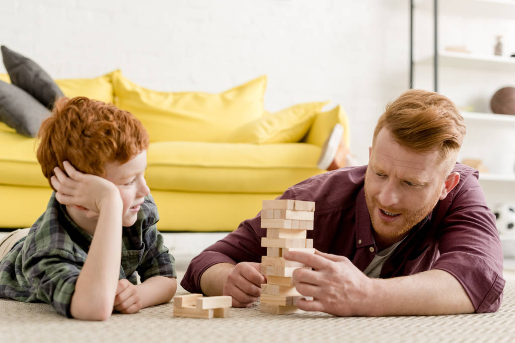 onnellinen punapää isä ja poika leikkivät puupalikoilla kotona
 - Valokuva, kuva