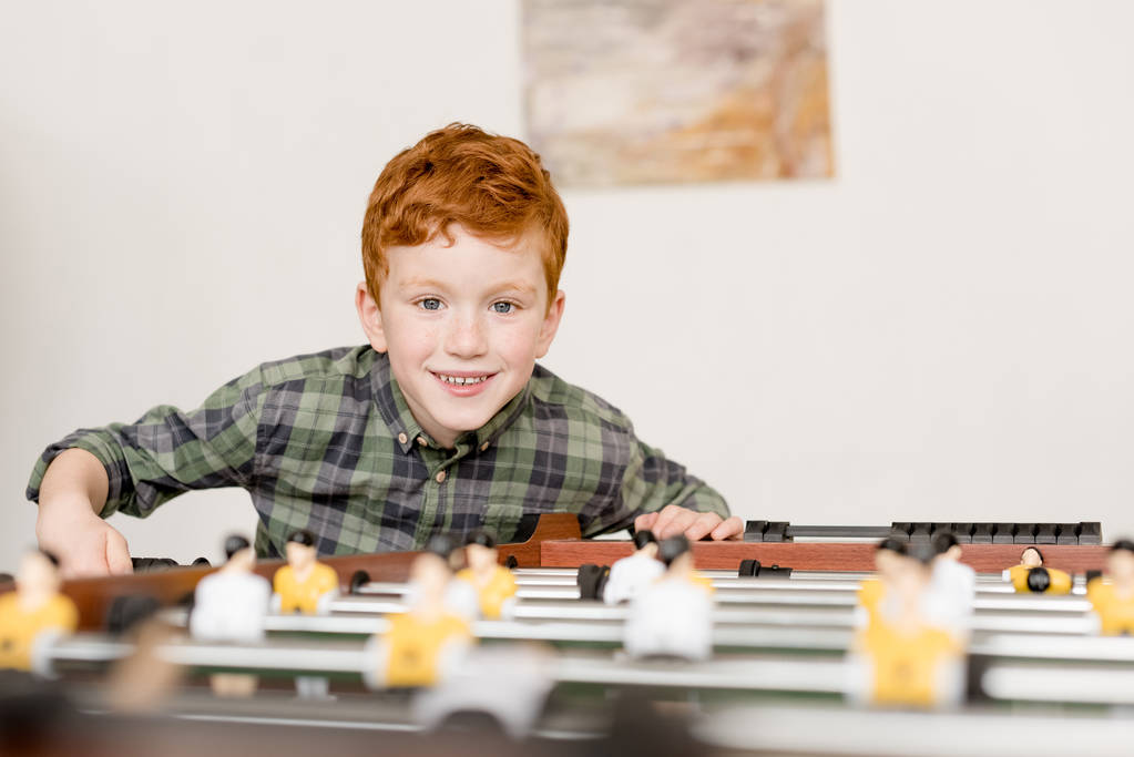 niedlich lächelnder kleiner Junge beim Tischkicker spielen - Foto, Bild