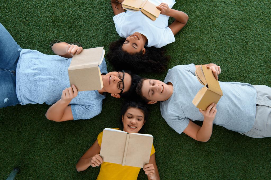 вид зверху групи студентів-підлітків, які читають книги на зеленій траві
 - Фото, зображення